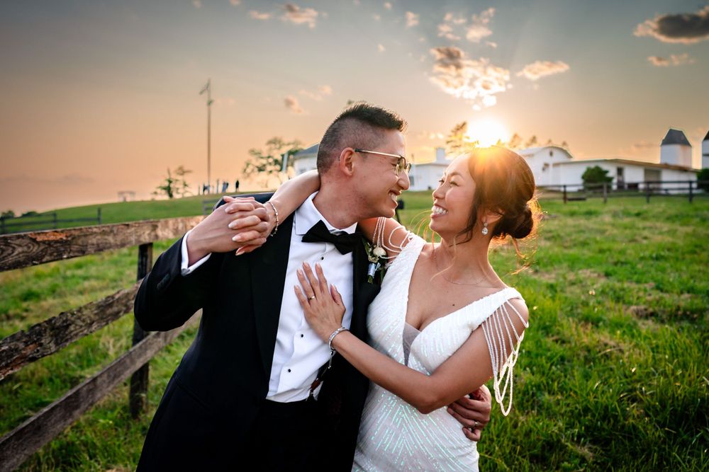 Sunset wedding portraits of couple embracing in a green meadow with golden light.