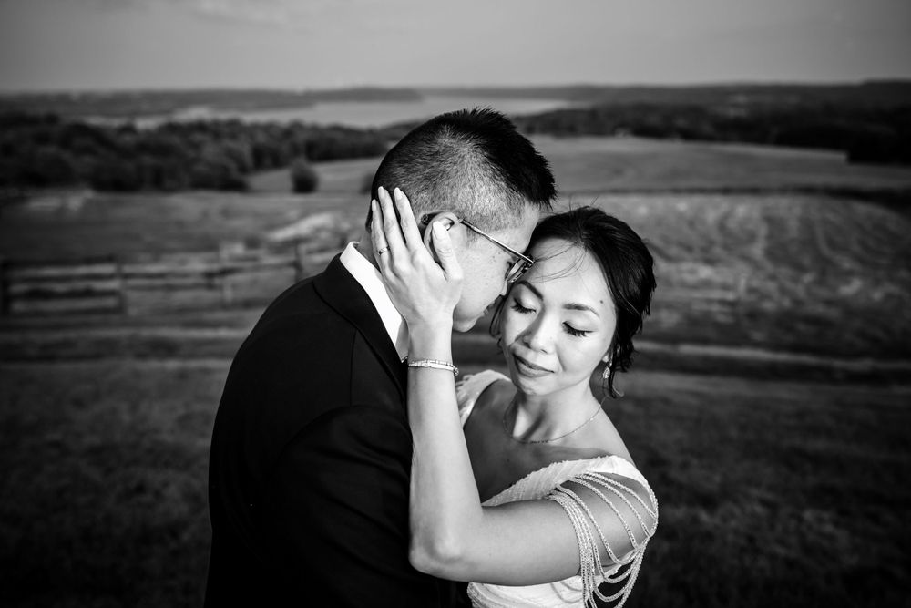 A romantic black and white wedding photo captured against a scenic mountain landscape.