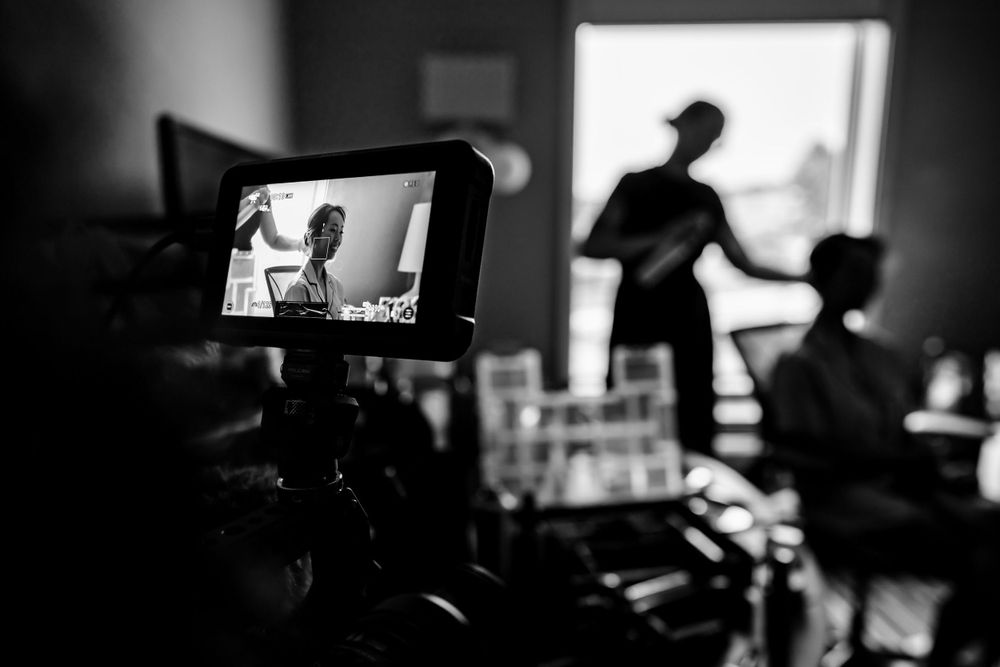 Silhouetted figures and camera equipment visible in dramatic black and white composition.