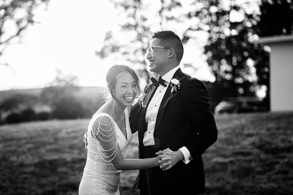 A playful black and white photo of a couple dancing outdoors.