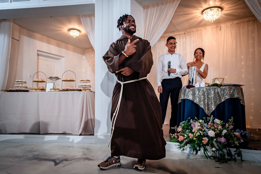 Wedding party dancing and celebrating at an elegant indoor reception with white drapes and floral decorations.