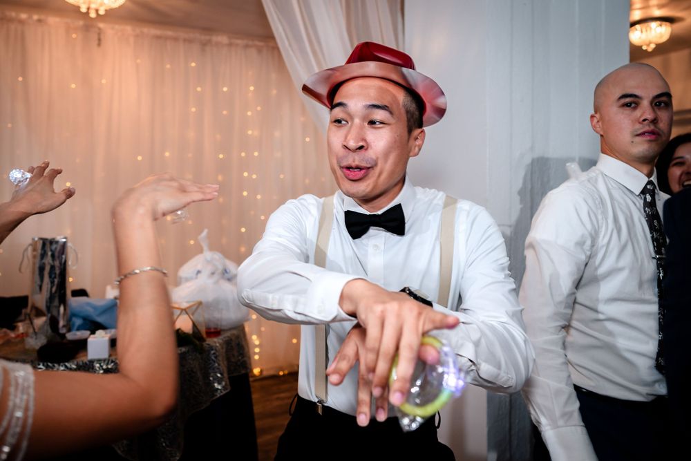 Wedding guests enjoying themselves on the dance floor at an indoor celebration.