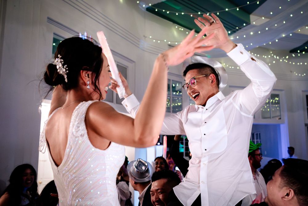 Energetic dancing and celebration under twinkling lights at a wedding reception.