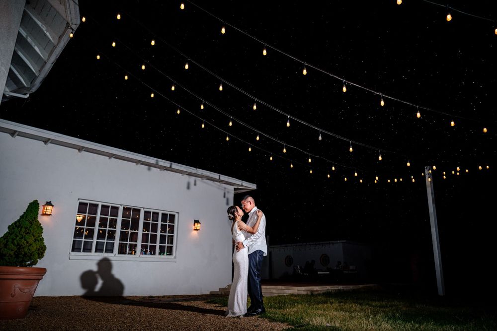 Romantic outdoor wedding venue at night illuminated by string lights.