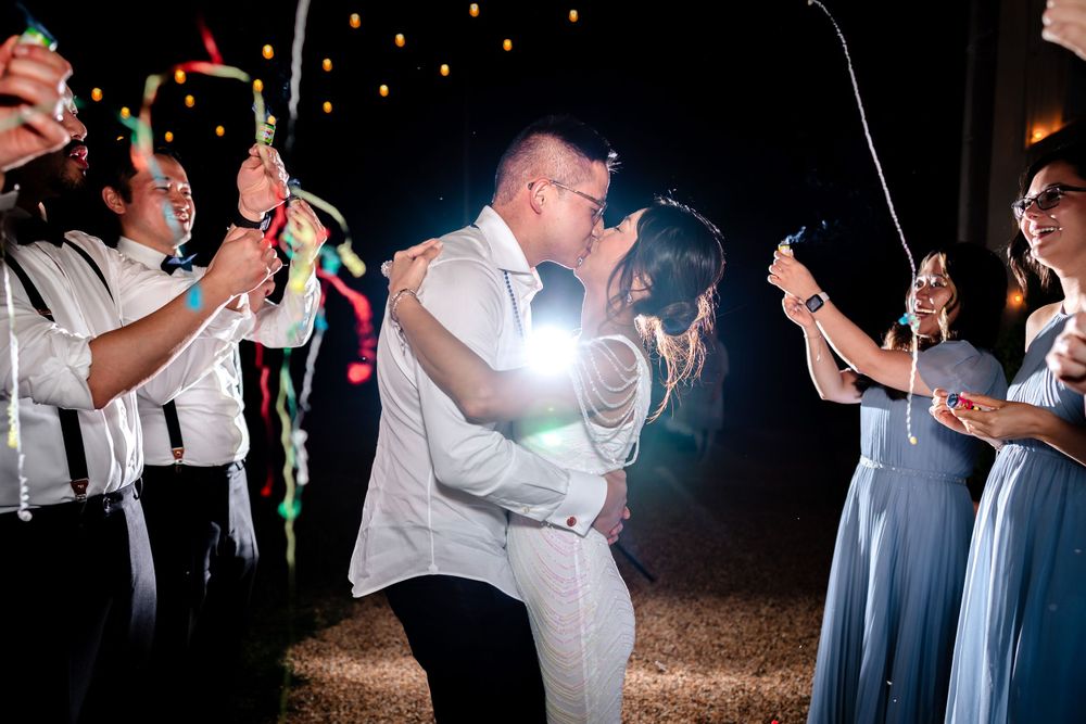 Wedding guests dancing and celebrating outdoors under string lights at night.