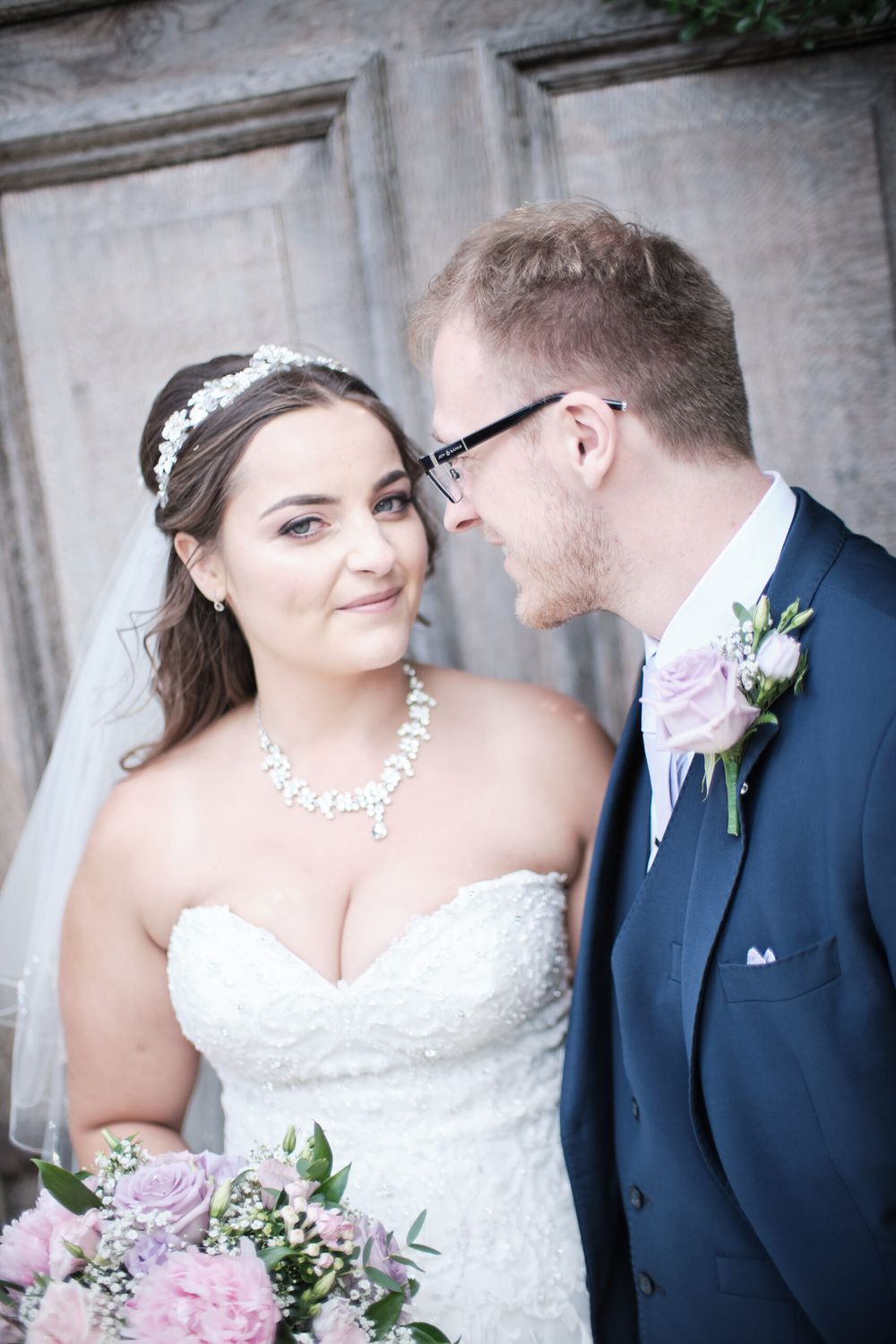 A romantic wedding portrait showing the couple in front of a textured stone wall.