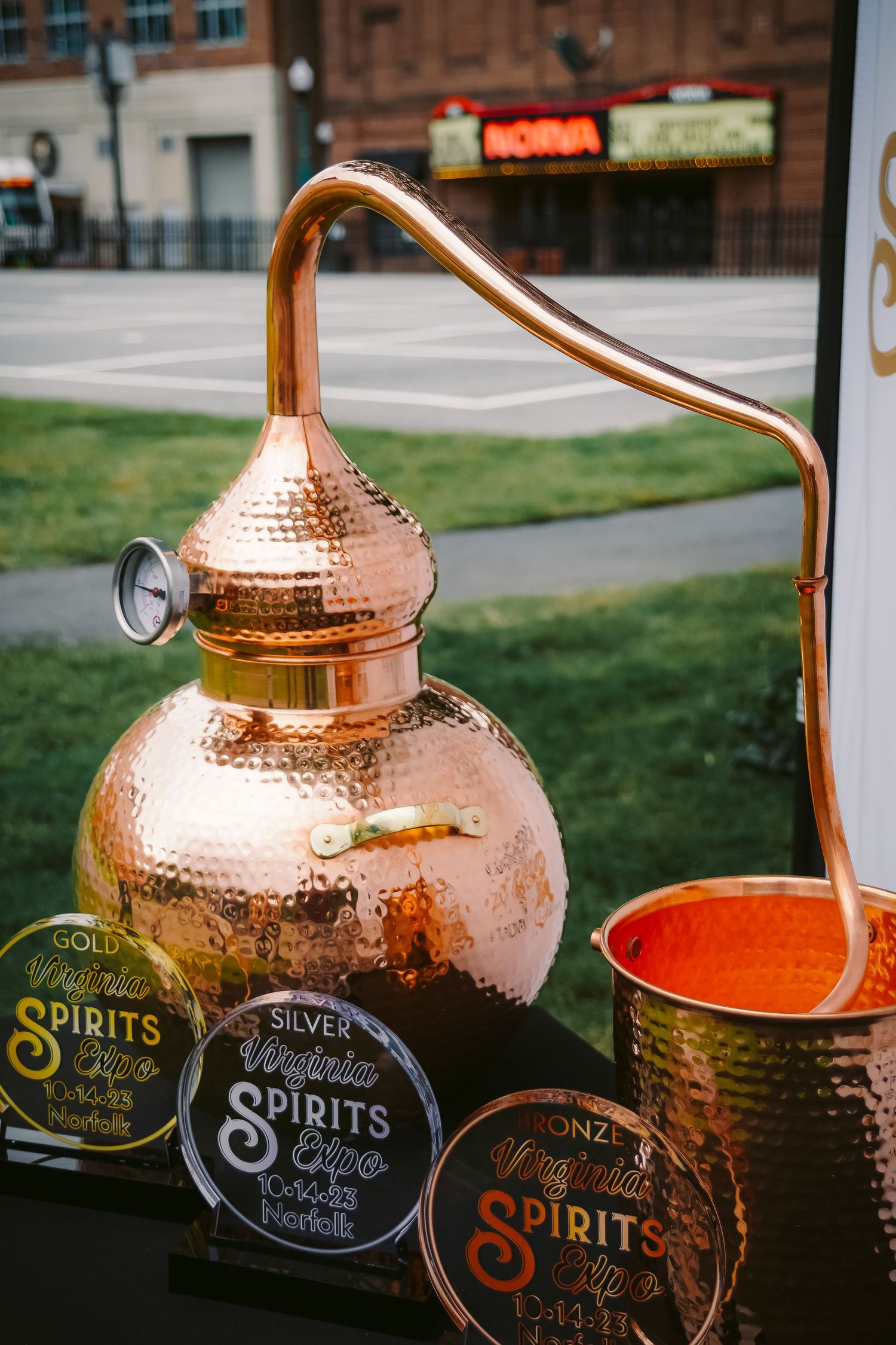 Copper distillation still with Spirit competition medals displayed at an outdoor event.
