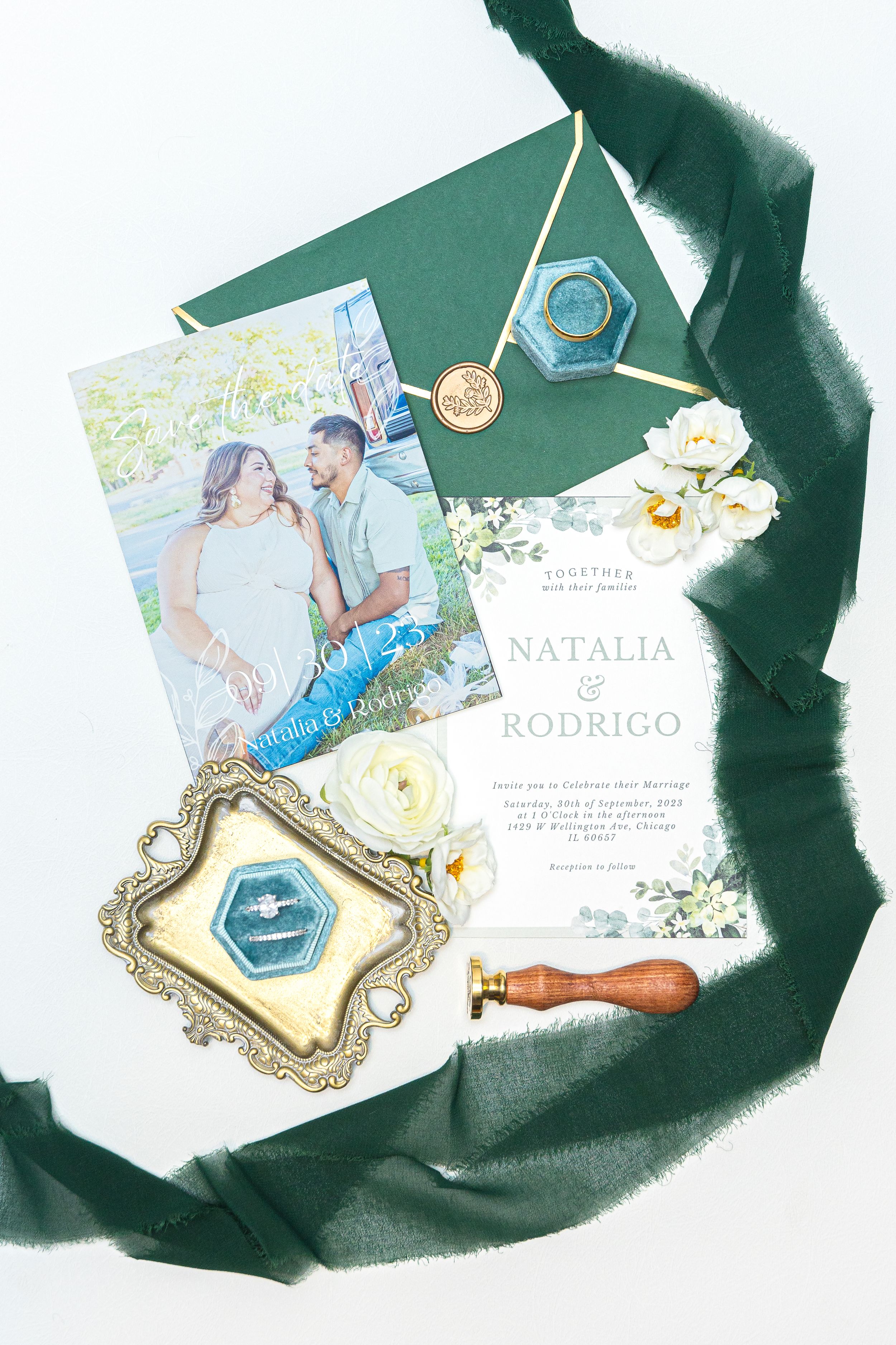 Wedding invitation with floral design and vintage frames arranged on emerald green fabric with romantic photography.