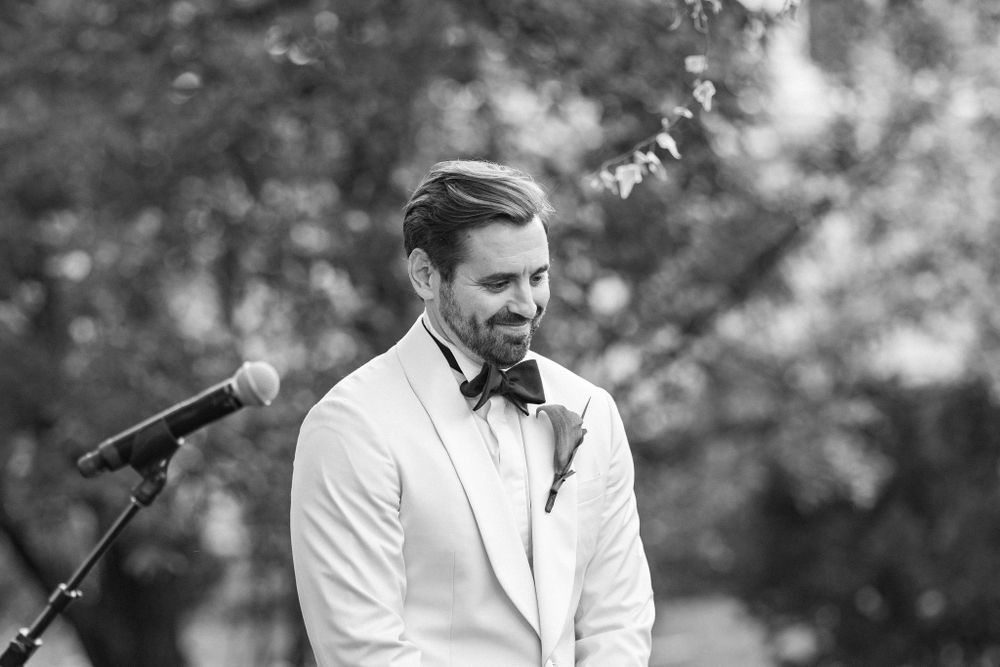 A black and white candid moment captured during an outdoor wedding ceremony.