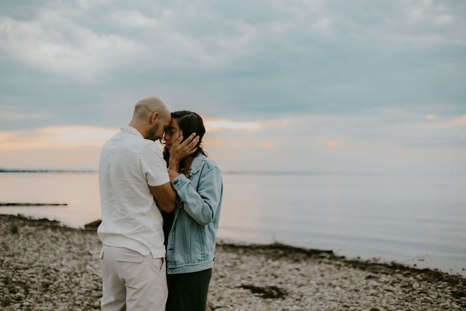 A couple sharing an intimate moment on a rocky beach at sunset.