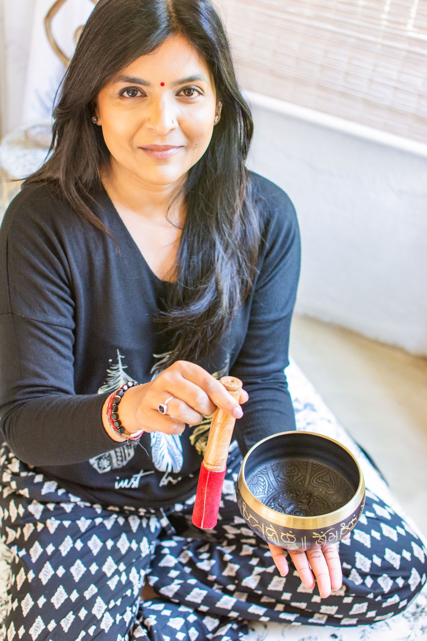 Person sitting cross-legged with traditional meditation bowl and red mallet.