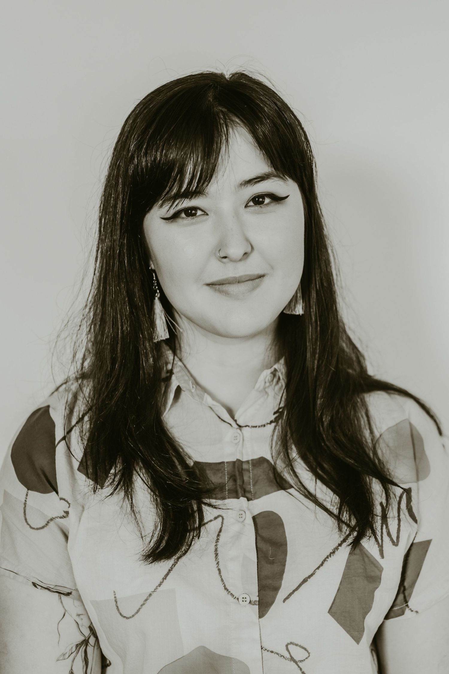 Black and white headshot of person wearing patterned shirt.