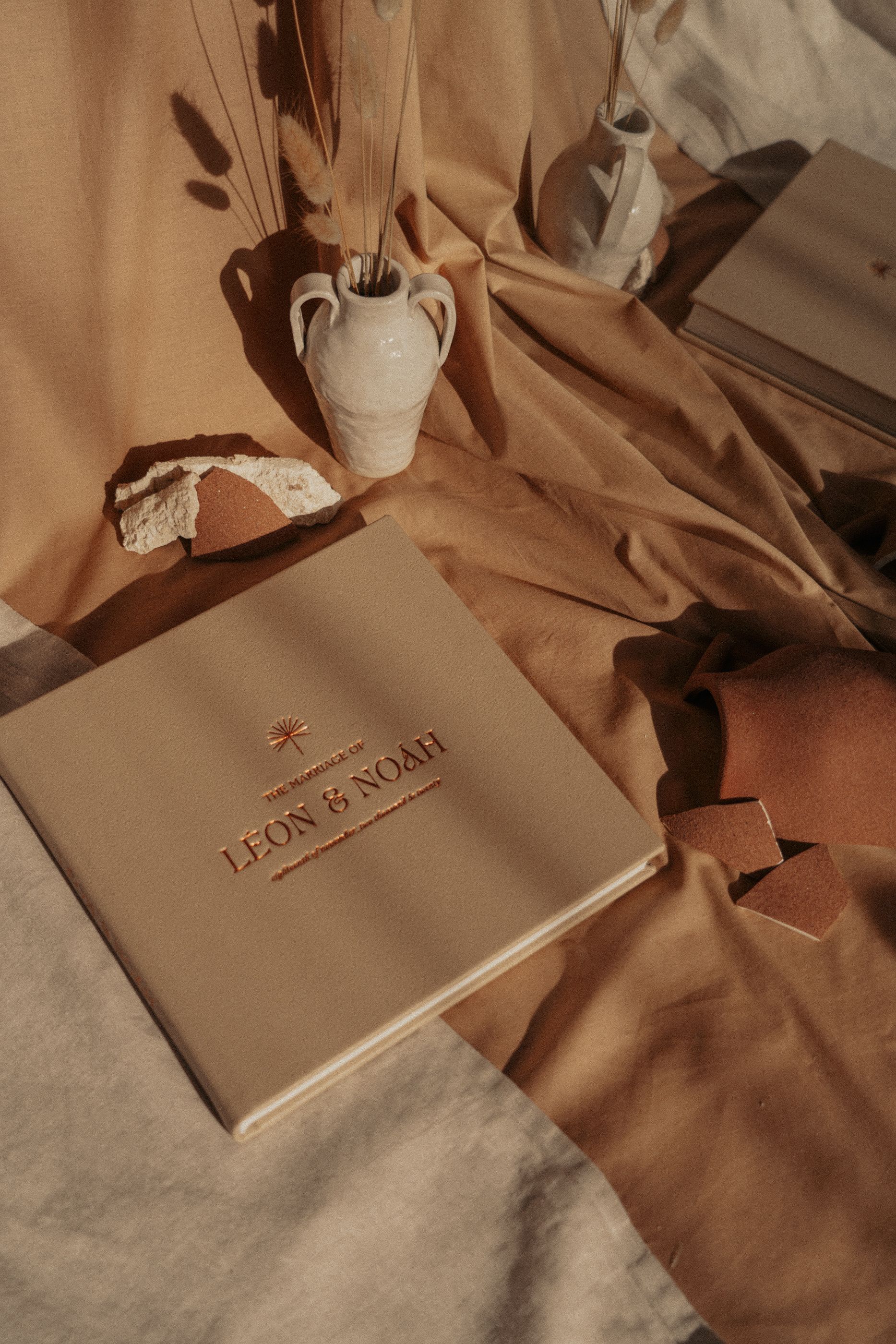 A styled product photo of Leon and Noah branding materials with a ceramic vase.