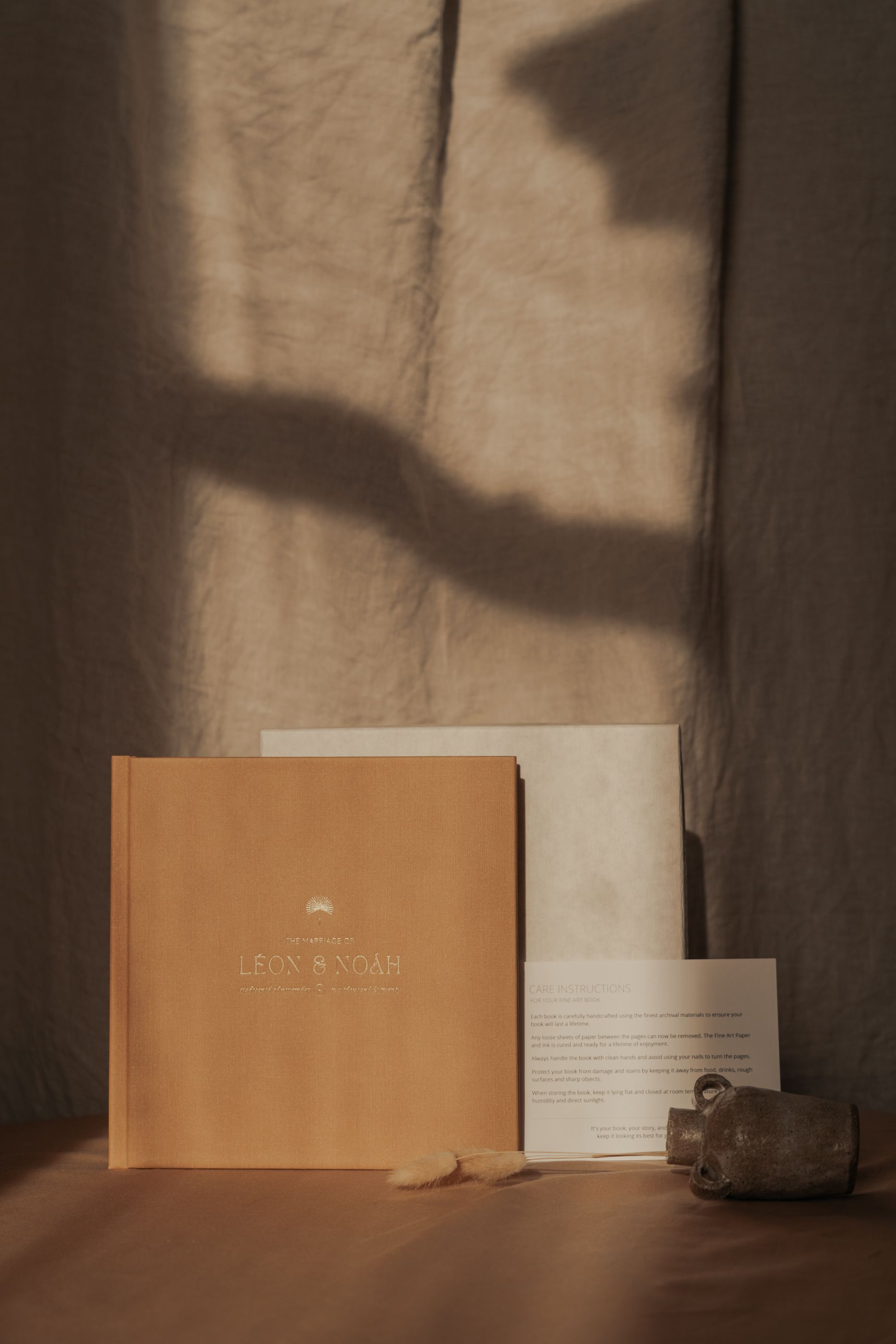 Minimalist product photography of Leon and Noah branding materials in warm lighting.
