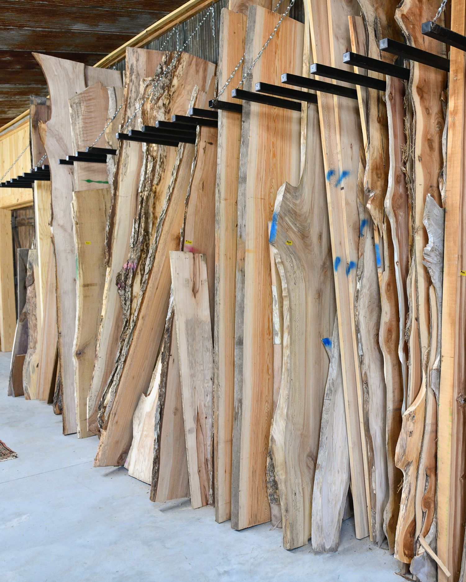 Collection of raw wood slabs stored vertically against a wall in a workshop.