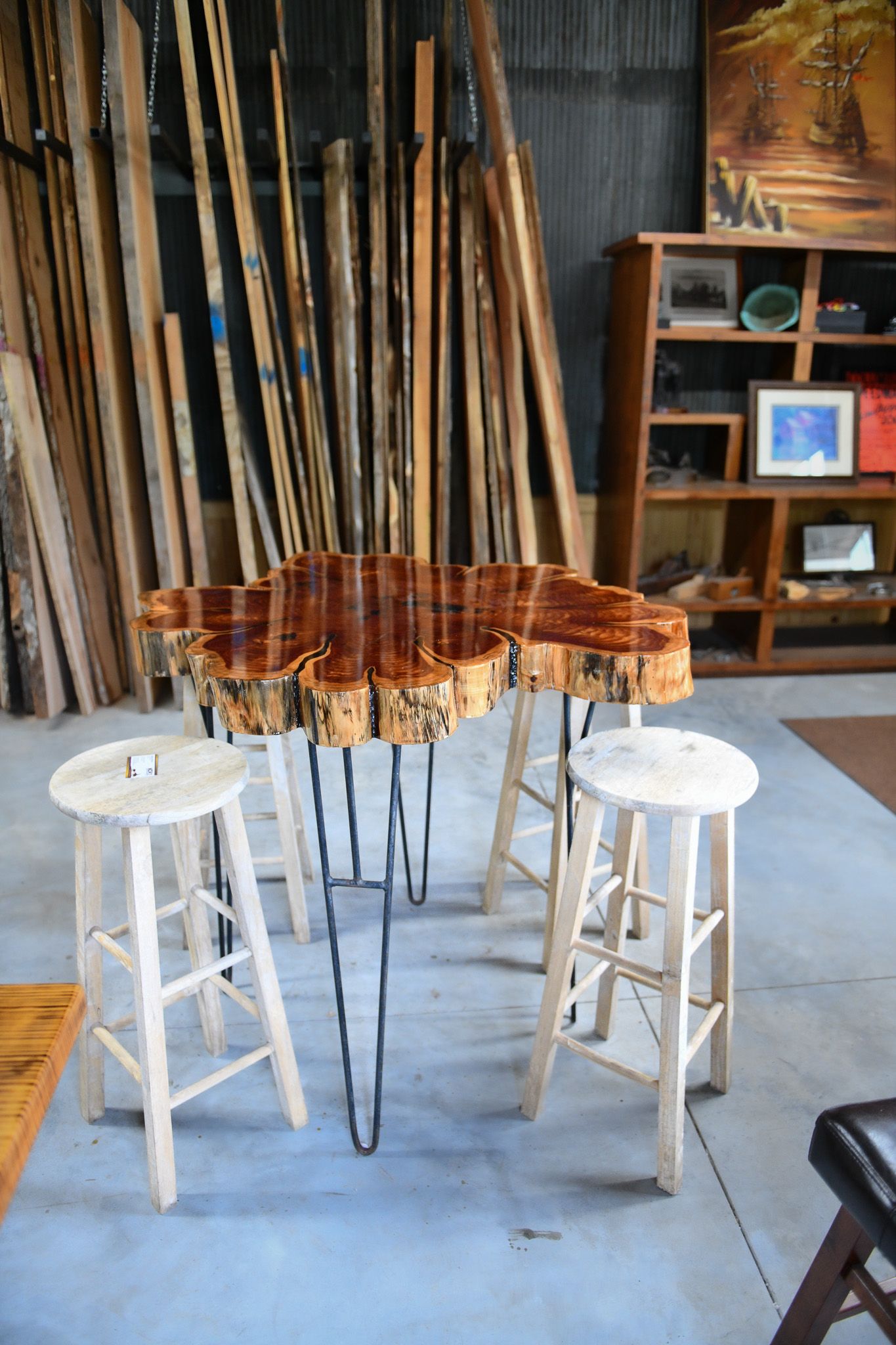 Modern live edge coffee table with hairpin legs flanked by white bar stools.