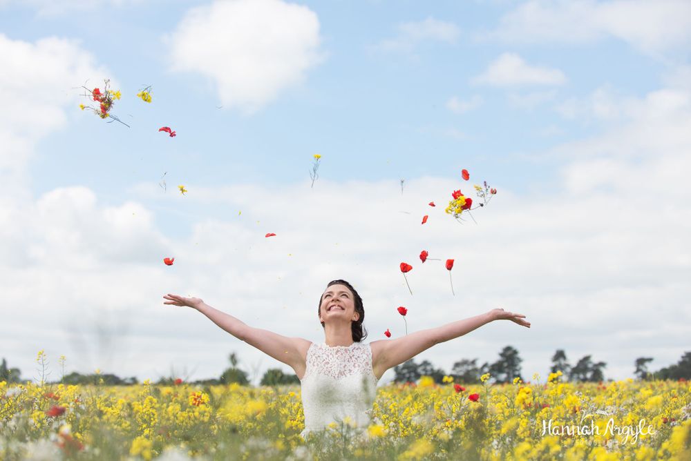 Woman in white dress twirls joyfully in a vibrant yellow wildflower field on a sunny spring day.