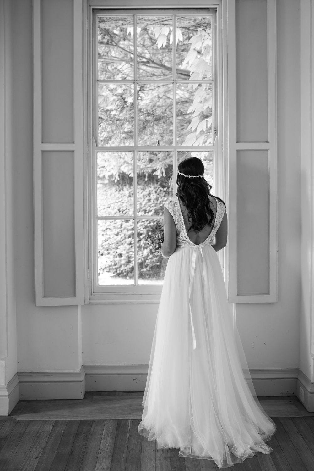 Wedding dresses on display in a bright white room with large windows showing a scenic outdoor view.