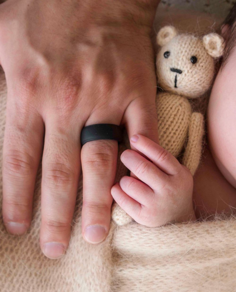 Newborn baby holds fathers fingers during newborn session with Queens photographer.