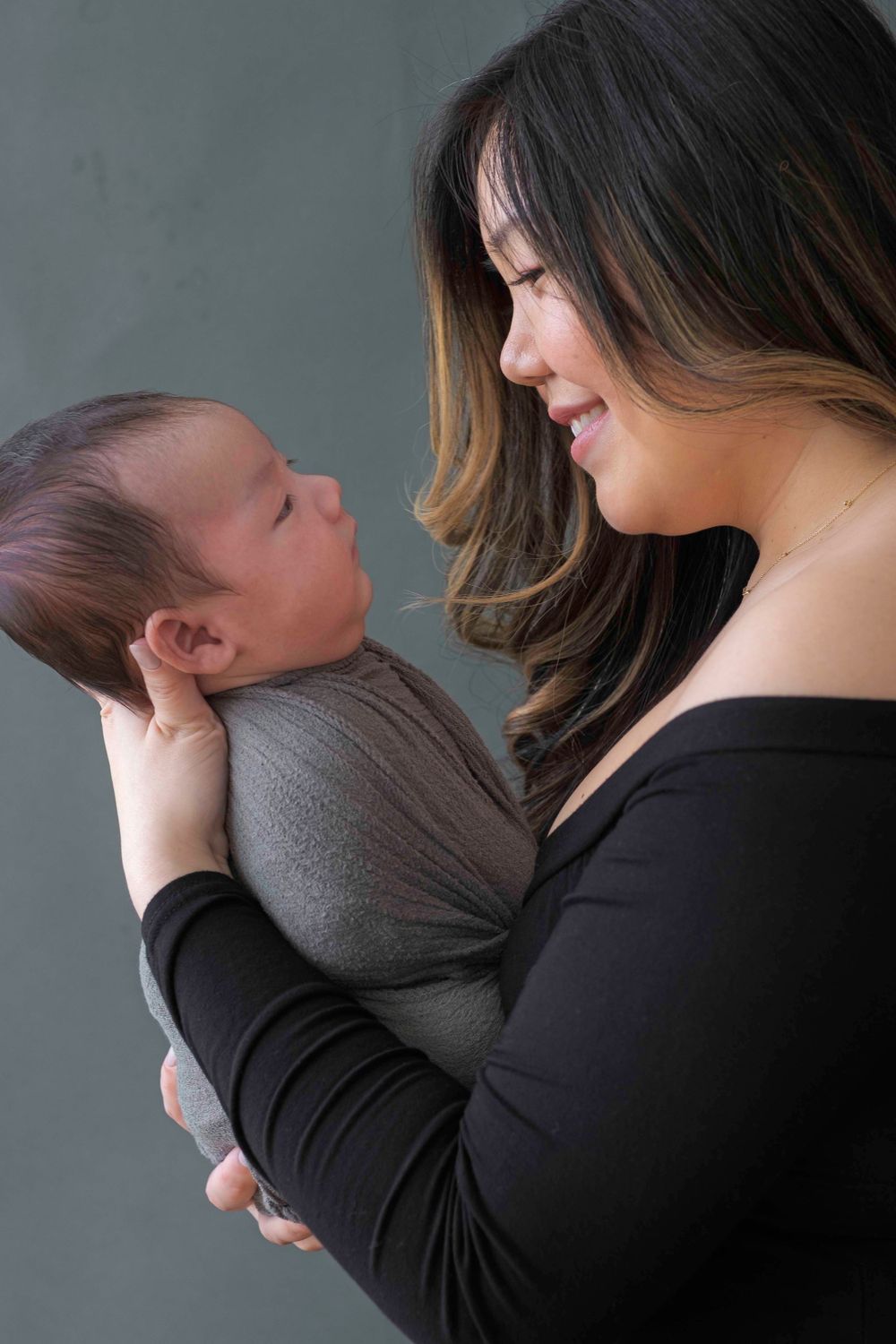 Mother hods newborn in her hands during newborn photo session with Queens photographer, Sweet Sol Photo.