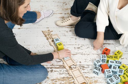 People sitting on white wooden floor playing with measuring tapes and numbers.