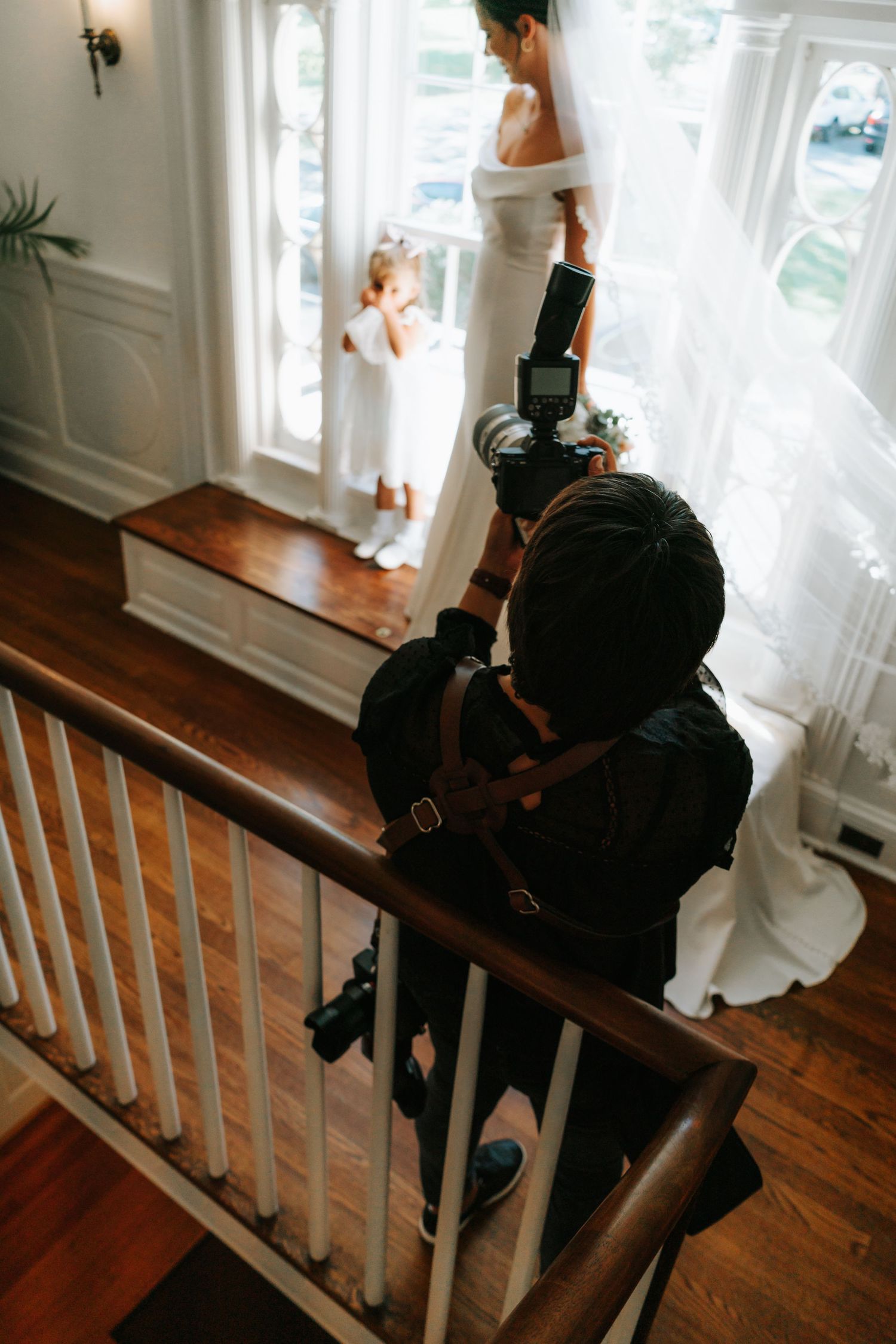 Professional photographer captures wedding preparations from a staircase angle in an elegant interior setting.