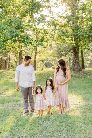 Family portrait in a serene forest setting with soft golden sunlight filtering through trees.