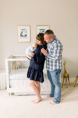 Tender moment between couple in nursery with white crib and giraffe decor.
