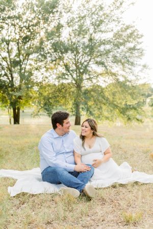 Couple sharing a loving moment while sitting on white blanket in a golden field.