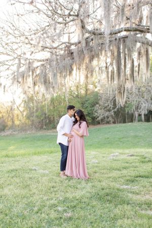Couple embracing in outdoor setting with Spanish moss draped trees.
