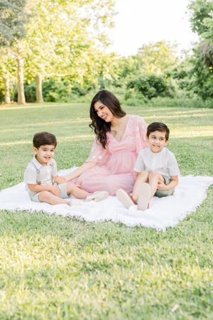 A family moment captured on a white blanket in a sunny park setting.