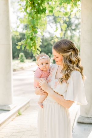 Elegant outdoor portrait between white columns with greenery overhead.