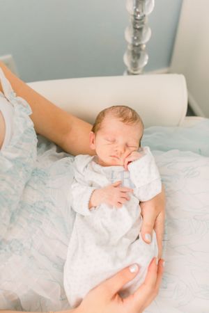 Sleeping newborn in white outfit resting peacefully on light blue bedding.