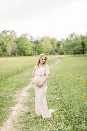Ethereal maternity portrait on a winding path through a wildflower meadow.