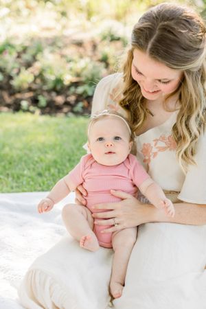 Intimate moment between parent and baby on white blanket in garden setting.