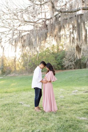 Intimate moment between couple under Spanish moss covered trees.