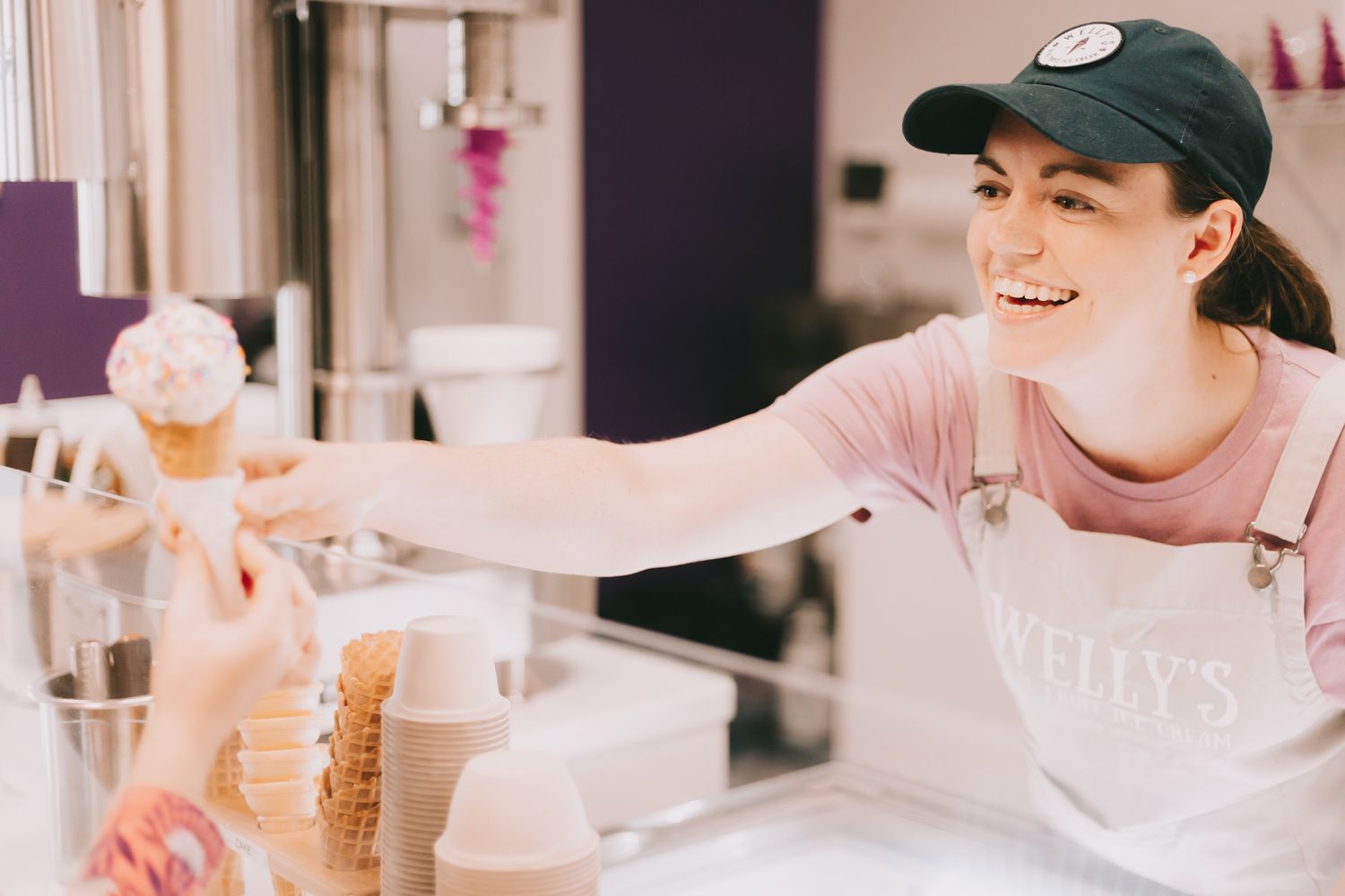 Woman in a black hat handing an ice cream cone
