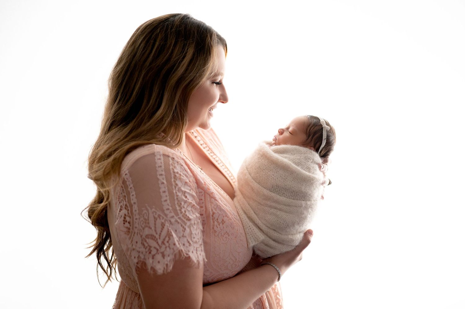 Silhouette portraits of parent and baby against bright white background.