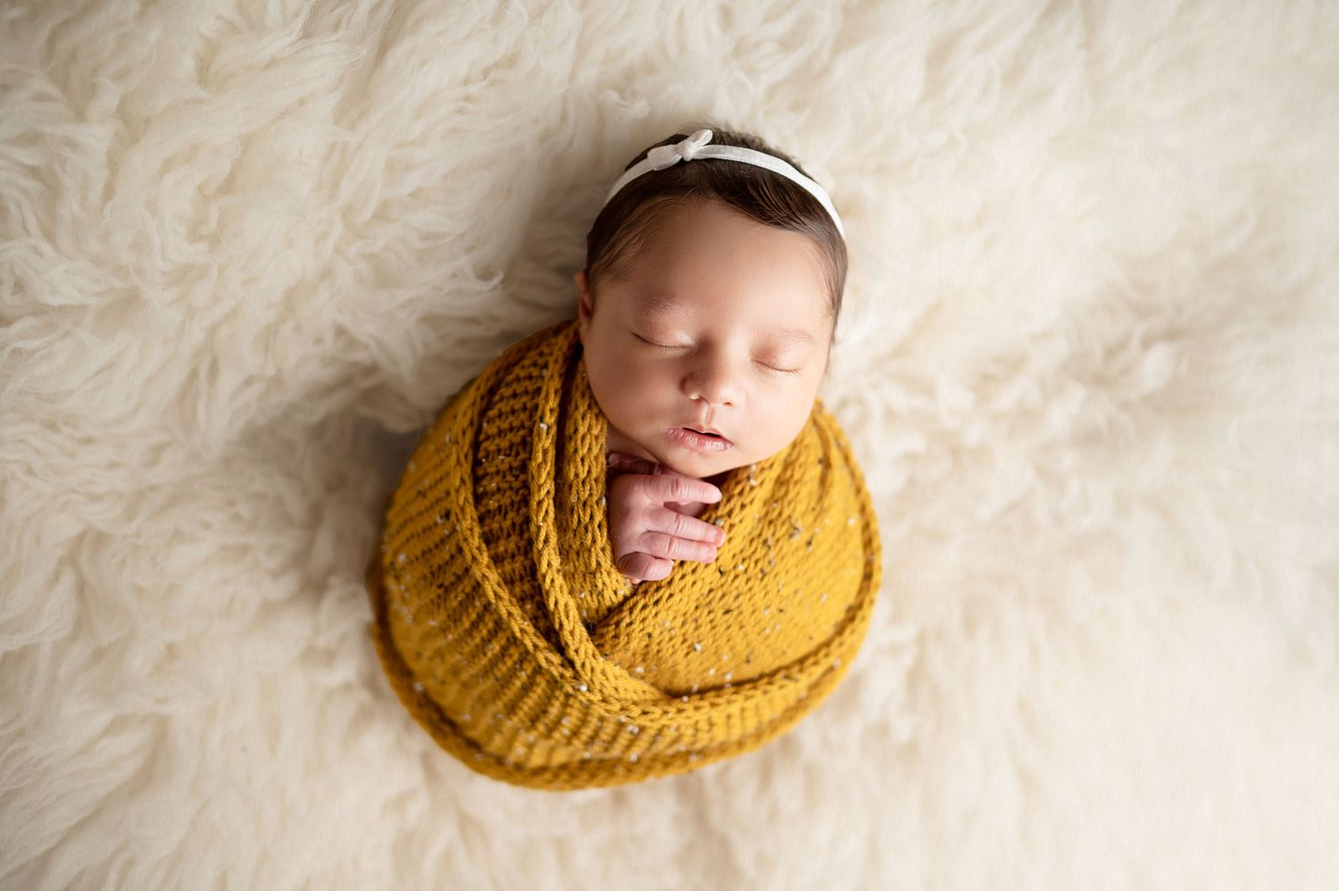 Creative newborn photo series featuring baby wrapped in mustard yellow knit wrap.