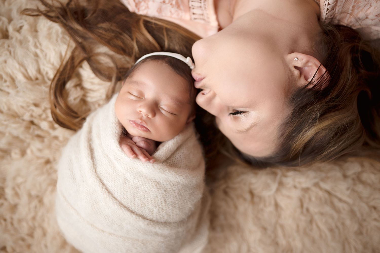 Portrait of newborn and sibling lying together on soft beige background.
