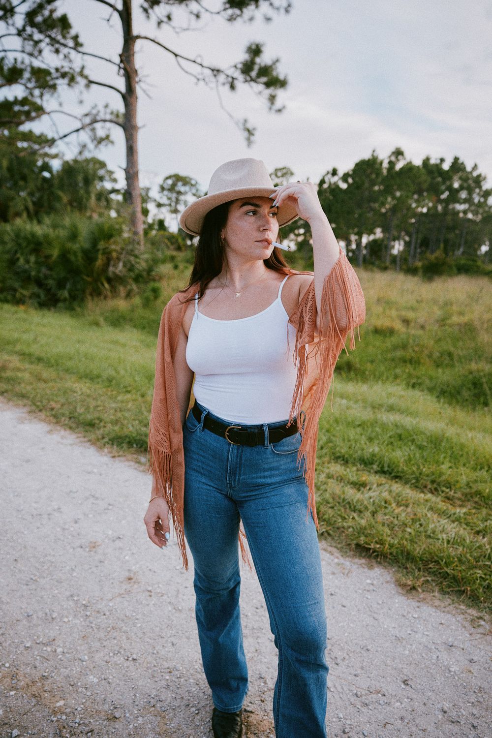 Casual western style outfit with hat and cardigan on nature trail.