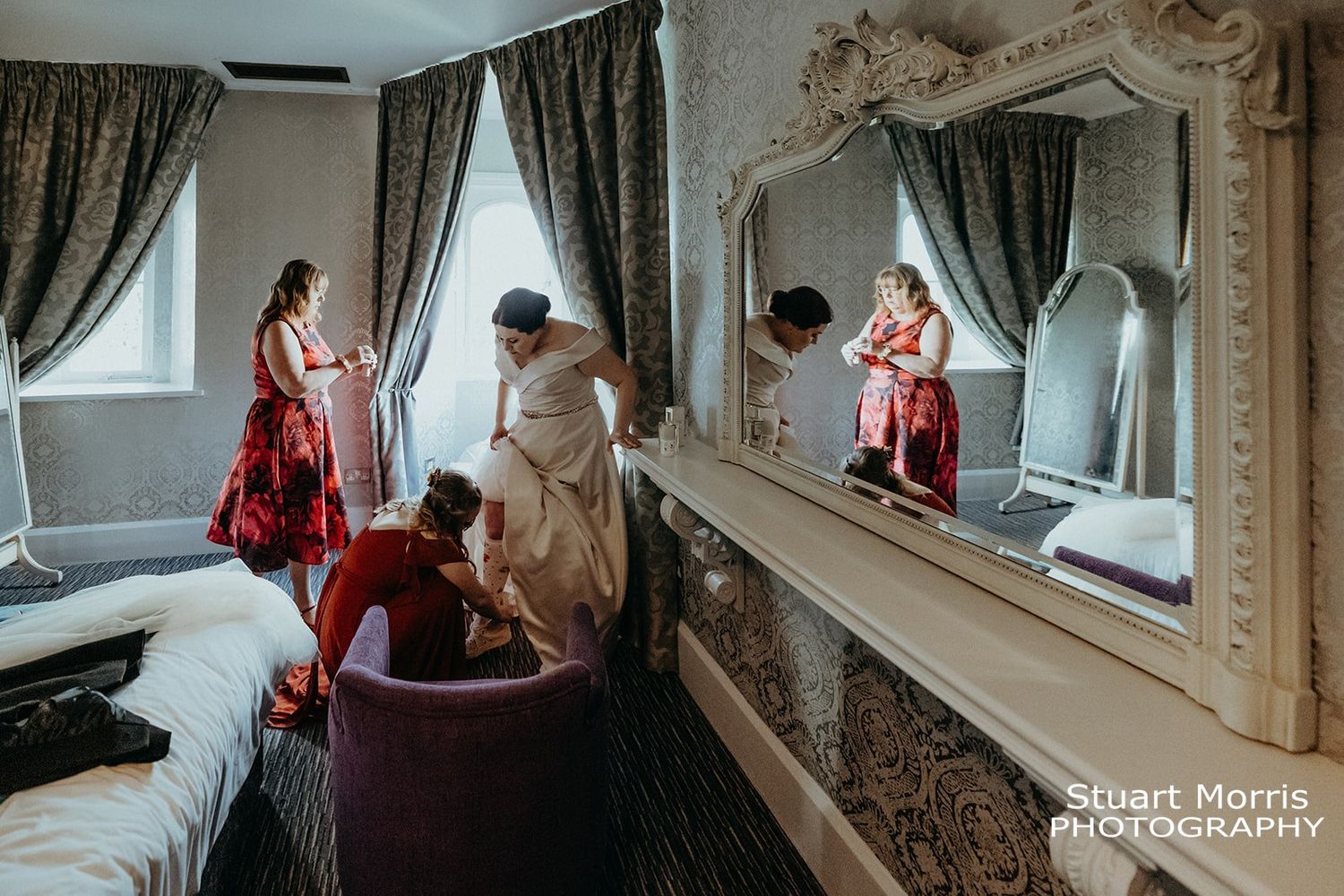 bridesmaid helps the bride put her wedding shoes on. Ruthin castle wedding.  Stuart Morris Photography