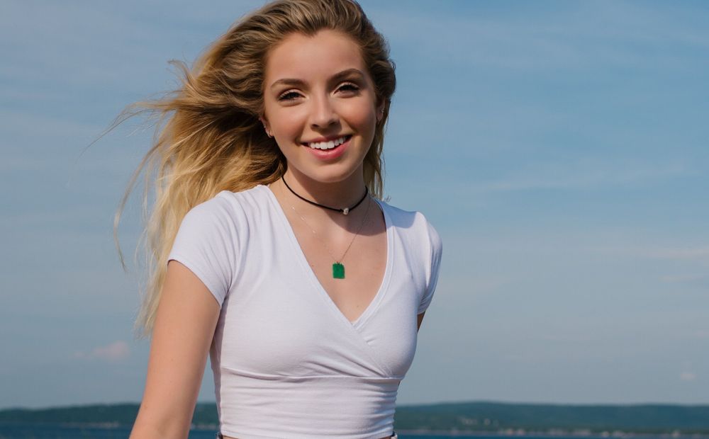 Casual summer portrait in white t-shirt against blue sky backdrop.