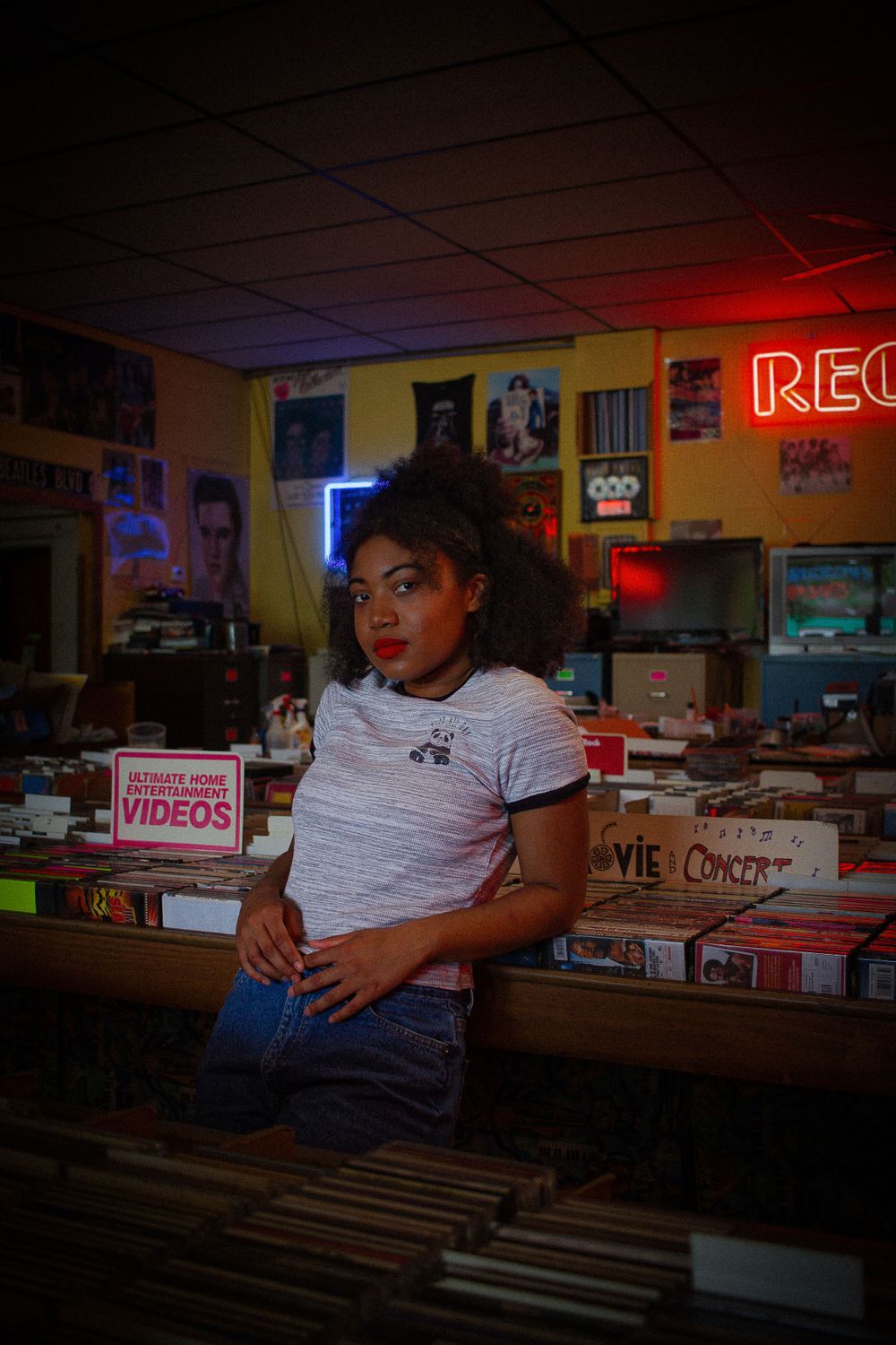 Interior of a music store with rows of albums and neon signage.