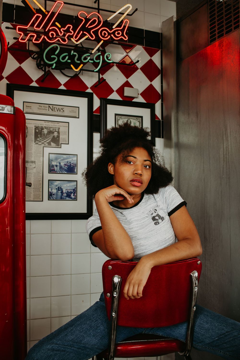 Person posing in vintage diner booth with red and white checkered decor.