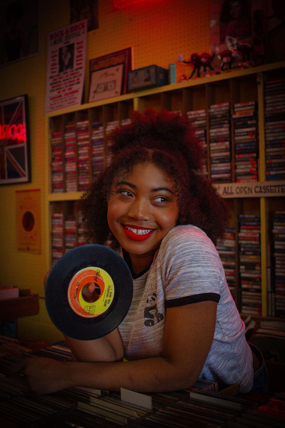 Person browsing vinyl records in a colorful record store with neon lighting.