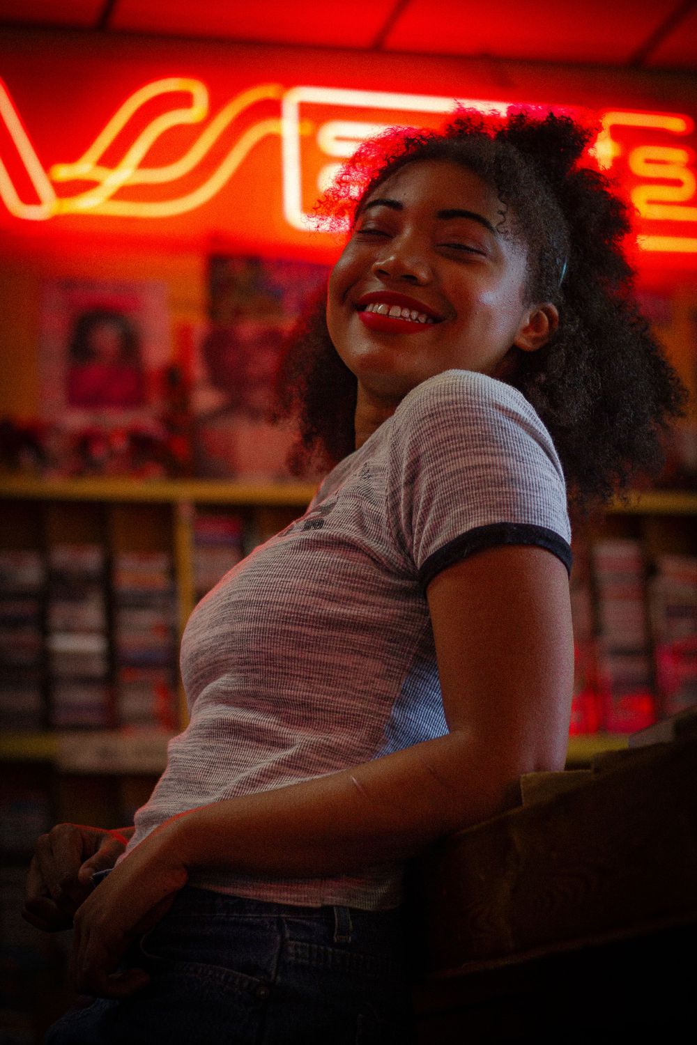 Person lounging in record store illuminated by red neon lights.