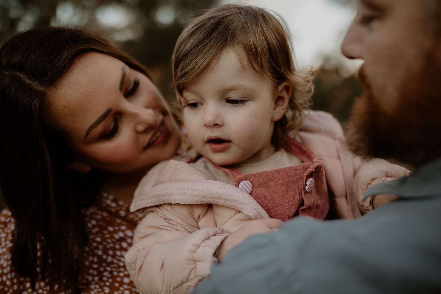 An intimate family moment outdoors with a child in pink clothing.