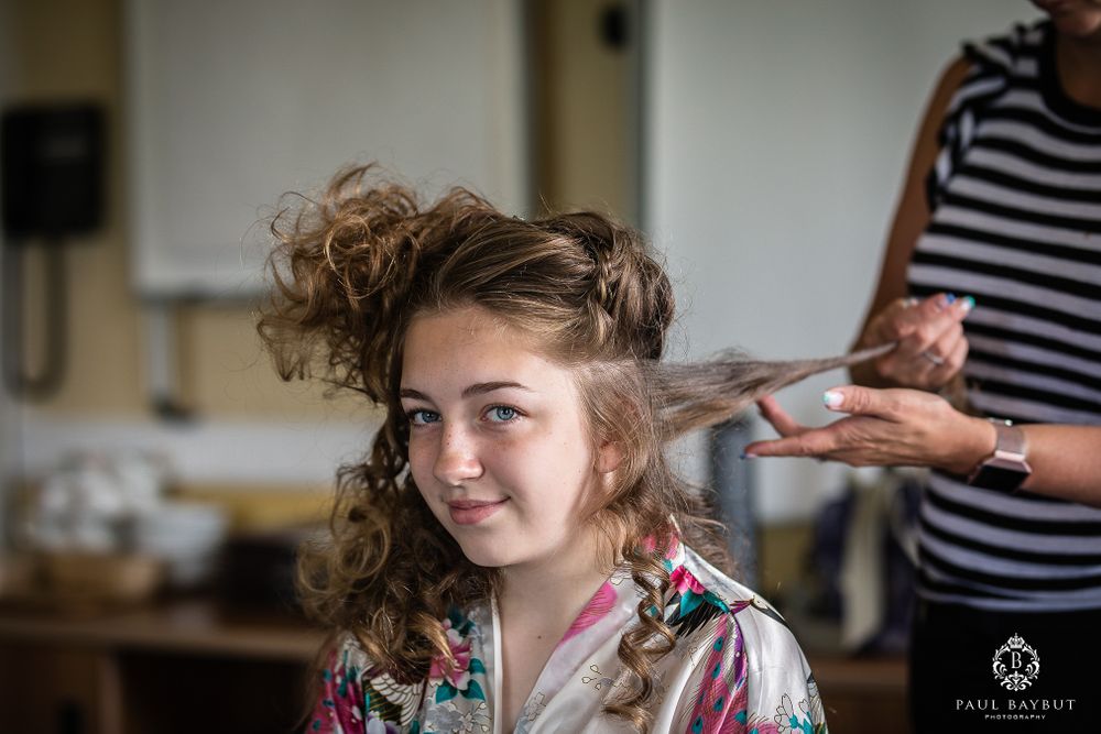 Stylist working on curling and styling hair during wedding day preparation.