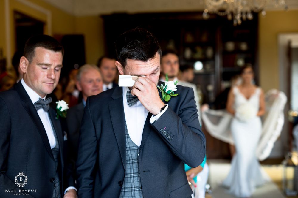 Emotional moment captured during wedding ceremony in an elegant room with chandelier.